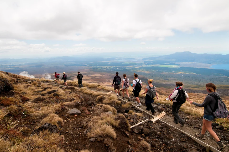 A group of nine hikers walking across the Tongariro Alpine Crossing.